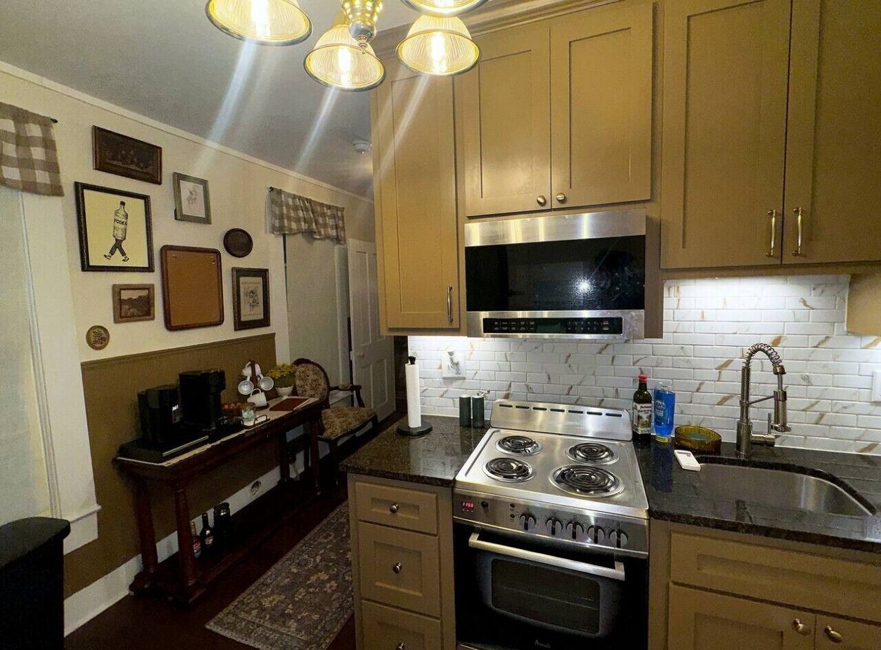 Una cucina con mobili in legno, un piano cottura in acciaio inossidabile e una parete rivestita in piastrelle.