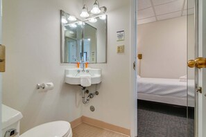 Un baño de hotel con lavamanos, inodoro y espejo con iluminación.