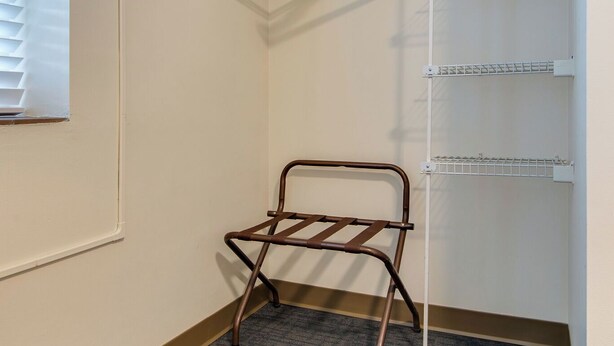Canto de um quarto de hotel com um escorredor de metal, um porta-toalhas branco e um termostato na parede.