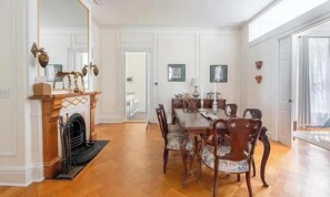 A dining room with a wooden table and chairs, a fireplace, and a mirror.