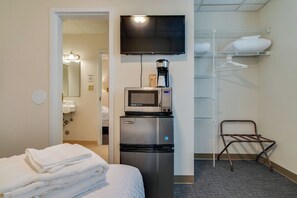 A hotel room with a bed, a microwave, a coffee maker, a TV, and a closet with shelves. - Perfect Suite for Travel on a Budget! Music Row!! (Nashville)