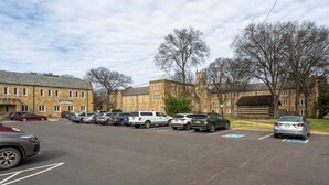 A parking lot with multiple cars and a building with a stone facade in the background. - Cozy Suite in a Historic Building! GREAT location (Nashville)