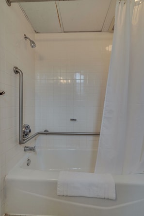 Ein Badezimmer mit einer weißen Badewanne, einer Dusche inklusive Duschbrause und einer Haltestange.