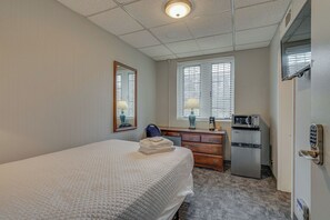 Ein Hotelzimmer mit Bett, Schreibtisch mit Mikrowelle, Kommode und Spiegel.