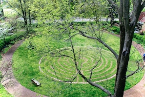 Un jardí circular amb un camí sinuós, una cadira i un arbre al primer pla.