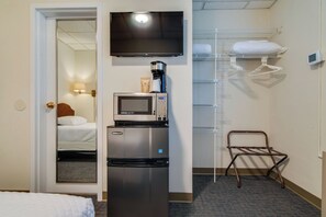 Ein Hotelzimmer mit Bett, Minibar, Fernseher, Mikrowelle, Kaffeemaschine, Kleiderhaken und Schuhablage.