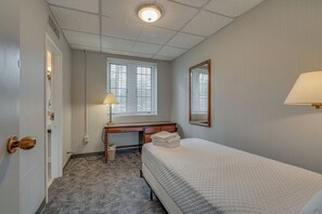 Een hotelkamer met een bed, bureau, lamp en een raam met zonwering.