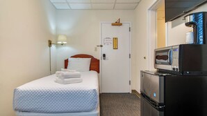 A hotel room with a bed, a nightstand, a refrigerator, and a microwave. - Unique Historic Dorm Suite in Prime Location (Nashville)