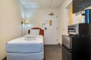 Ein Hotelzimmer mit Bett, Nachttisch, Kühlschrank und Mikrowelle.