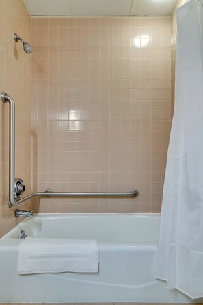 Ein Badezimmer mit einer Badewanne, einem weißen Handtuch, einer Duschvorhang und einer Haltestange.