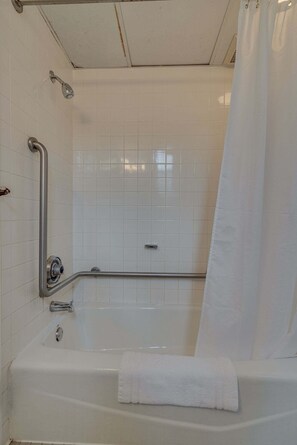 Een badkamer met een bad, een douche en een handgreep.