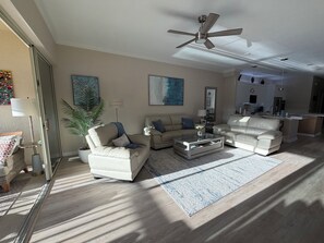 A spacious living area with a ceiling fan, a sofa, a coffee table, and a rug.