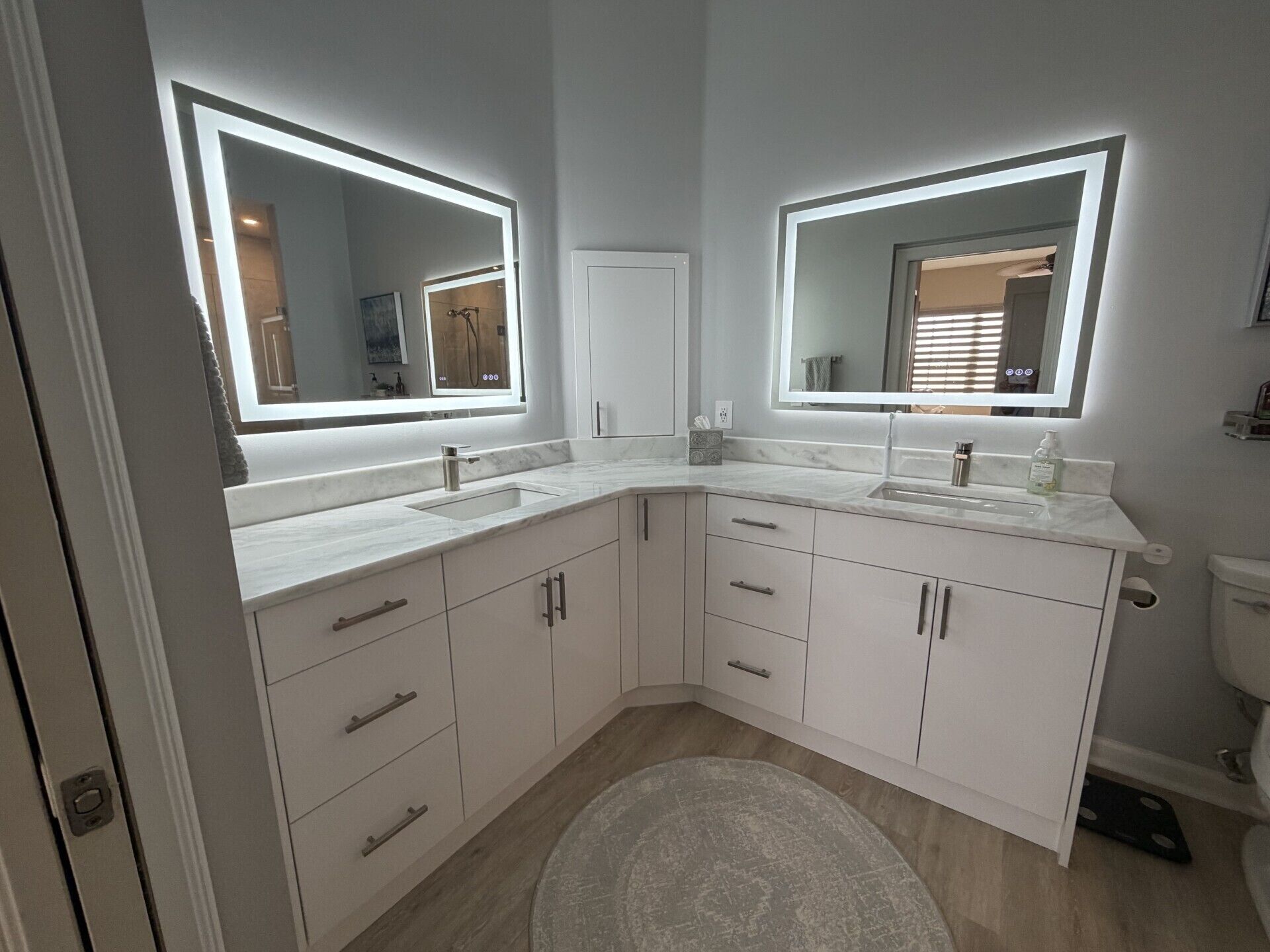 Een moderne badkamer met twee grote spiegels, een wastafel en een toilet.