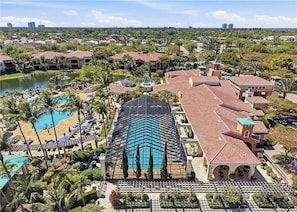 A resort with multiple buildings, a large swimming pool, and a beach area.