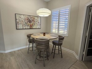 A dining area with a round table, six chairs, a pendant light, and a window with blinds. - Resort Like Living!  Walk to Coconut Point in Beautiful Rapallo in Estero! (Estero)