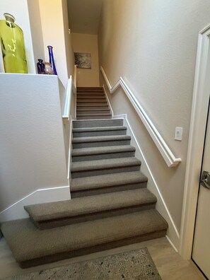 Una escalera alfombrada con barandilla que lleva a una puerta.