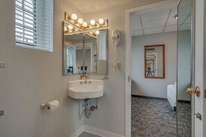 Ein Badezimmer mit Waschbecken, Spiegel, Schminklicht und Föhn.