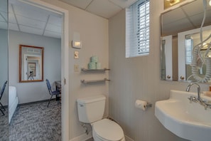A bathroom with a toilet, sink, mirror, and a small window. - Unique Suite in Great Location - on Music Row! (Nashville)