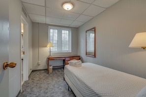 A hotel room with a bed, a desk, a lamp, and a window with blinds. - Unique Suite in Great Location - on Music Row! (Nashville)