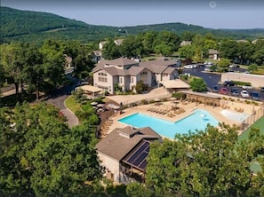 Ein großes Haus mit Swimmingpool, umgeben von Bäumen und einer hügeligen Landschaft.