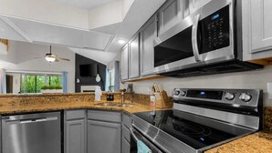 Una cocina moderna con electrodomésticos de acero inoxidable, encimeras de granito y horno empotrado.