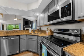 A modern kitchen with stainless steel appliances, granite countertops, and a built-in oven. - The Luxe @ Pointe Royale Resort (Branson)