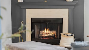 Una chimenea encendida, un faldón gris y una cesta tejida a la derecha.