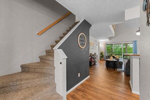 Eine Treppe führt zu einem Wohnbereich mit Esstisch und Stühlen, einem Sofa und Blick ins Freie.