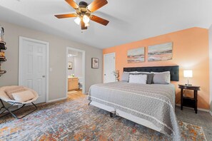 A bedroom with a bed, a ceiling fan, a nightstand, a chair, and a rug. - The Luxe @ Pointe Royale Resort (Branson)