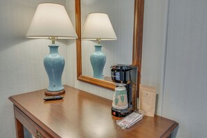 Een houten tafel met een koffiezetapparaat, afstandsbedieningen en een lamp.