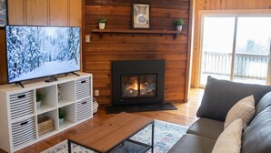 Una sala de estar acogedora con televisión, chimenea, sofá y paneles de madera.