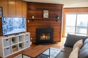 Ein gemütliches Wohnzimmer mit Fernseher, Kamin, einer Couch und Holzvertäfelung.