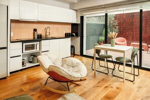 A modern kitchen with white cabinets, a black countertop, and a dining area with a table and chairs. - Modern Escape in Vibrant Roma Norte (México D.F.)