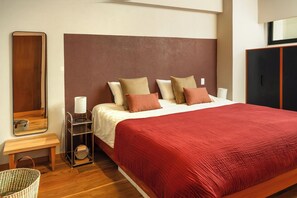 A bedroom with a bed, a bedside table, a mirror, a wardrobe, and a floor lamp. - Modern Escape in Vibrant Roma Norte (México D.F.)