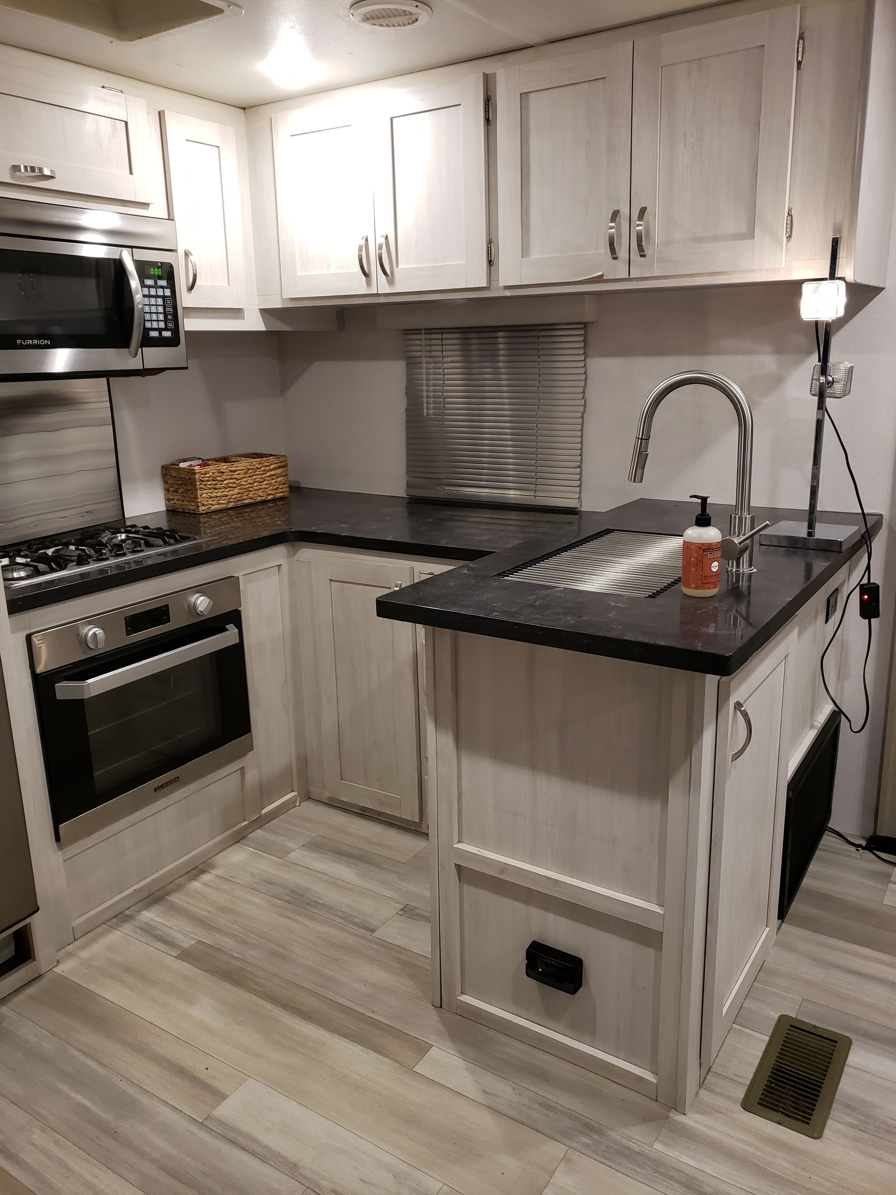 A compact kitchen with a microwave, oven, and sink.