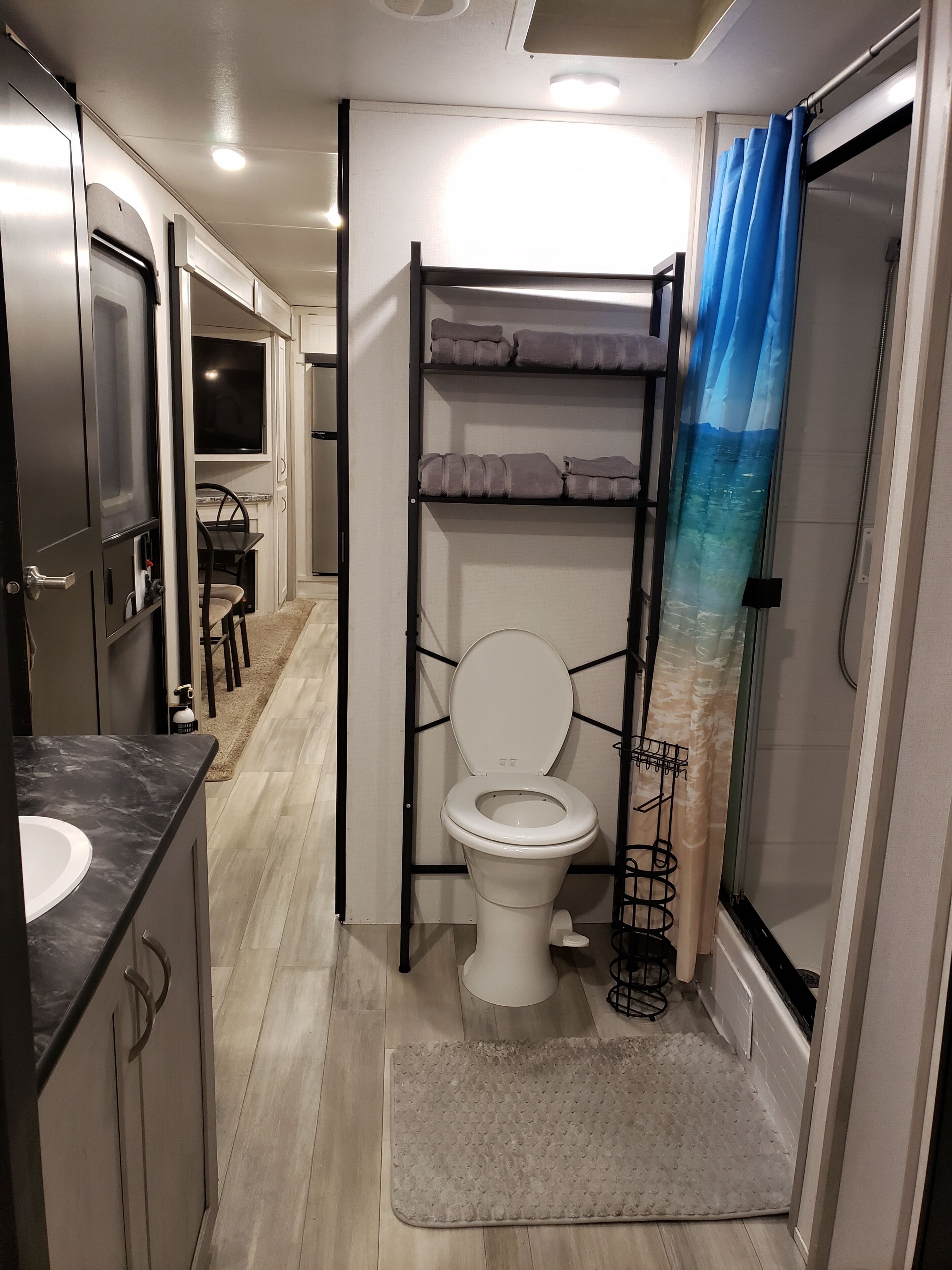 Ein kleines Badezimmer mit Toilette, einer Dusche mit blauer Duschkabine und einem kleinen Waschbecken.