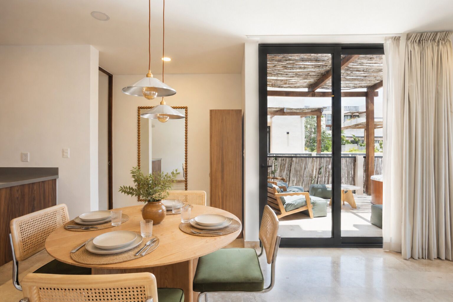 A dining area with a round table, chairs, and a vase of flowers.
