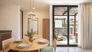 A dining area with a round table, chairs, and a vase of flowers. - RBK Departamento 2026 AC (Tulum)