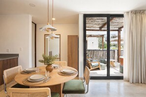 A dining area with a round table, chairs, and a vase of flowers. - RBK Departamento 2026 AC (Tulum)