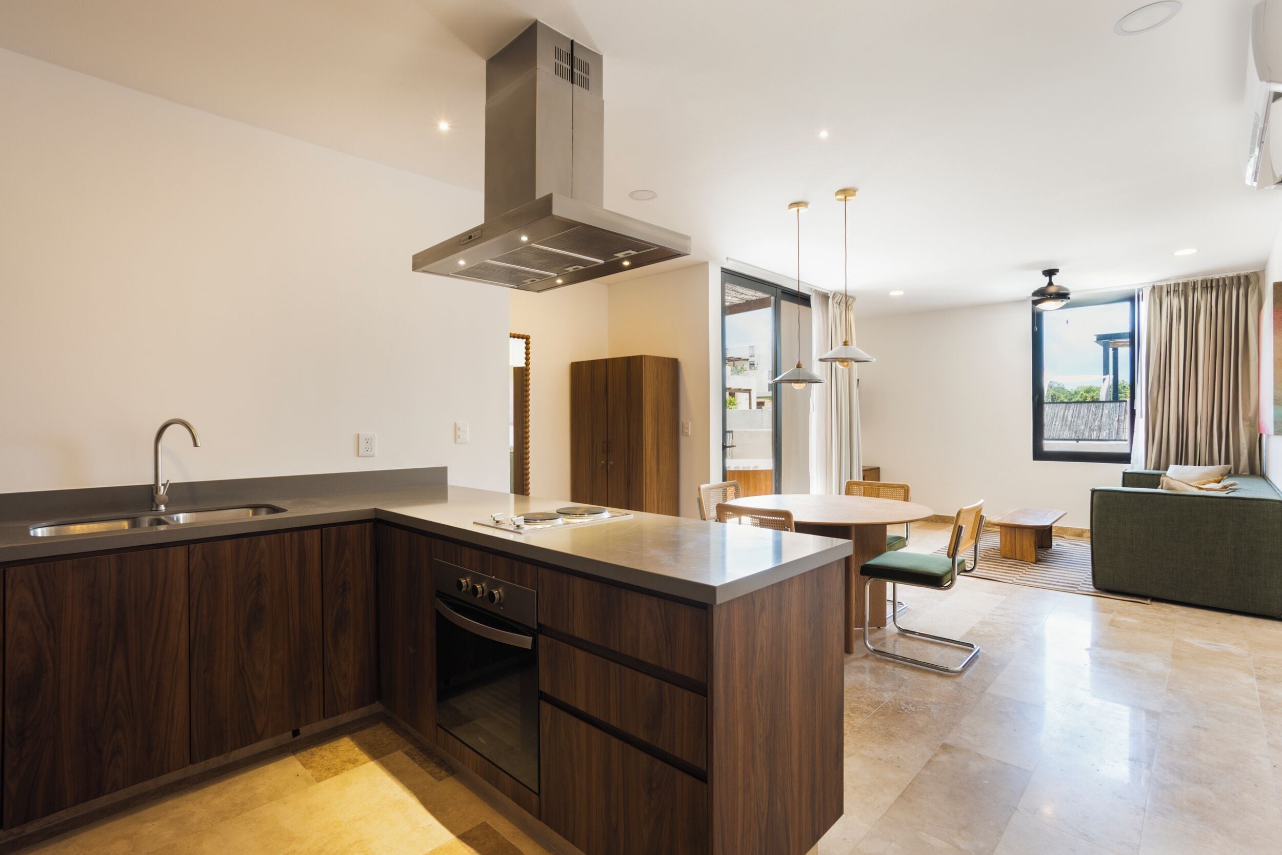 A modern kitchen with a built-in oven, a large island, and a dining area with a table and chairs.