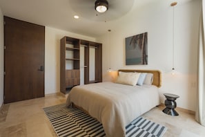 A bedroom with a bed, a wardrobe, a nightstand, a lamp, and a painting on the wall. - RBK Departamento 2026 AC (Tulum)