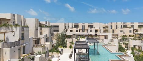 Ein modernes Resort mit mehreren Gebäuden, einem zentral gelegenen Pool und Außenbereich-Sitzgelegenheiten.