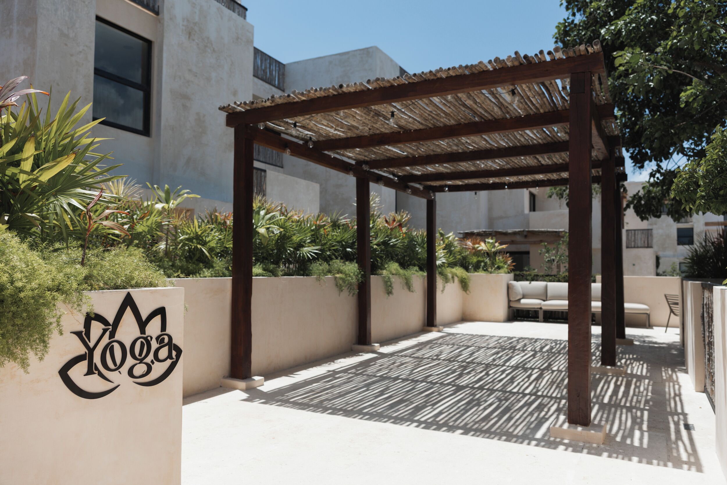 Un espace extérieur abrité, doté d’une pergola, d’un coin salon et d’un mur orné d’un logo.