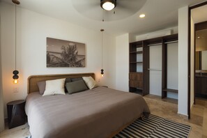 A bedroom with a large bed, a nightstand, a wall-mounted lamp, a ceiling fan, and a wardrobe. - RBK Departamento 2026 AC (Tulum)