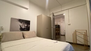 Ein Schlafzimmer mit Bett, Kleiderschrank, einem Bild und einer Tür zu einem anderen Raum.