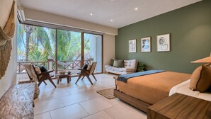 A modern bedroom with a large bed, a sofa, a dining table, and a balcony with a view of trees. - Elegant 2BR Jungle Sanctuary Private Terrace Pool Access (Higuera Blanca)