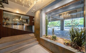 A reception area with a counter, a staircase, and a window with a view of the outside. - Busan Sasang Mr. Brick Hotel (Busan)