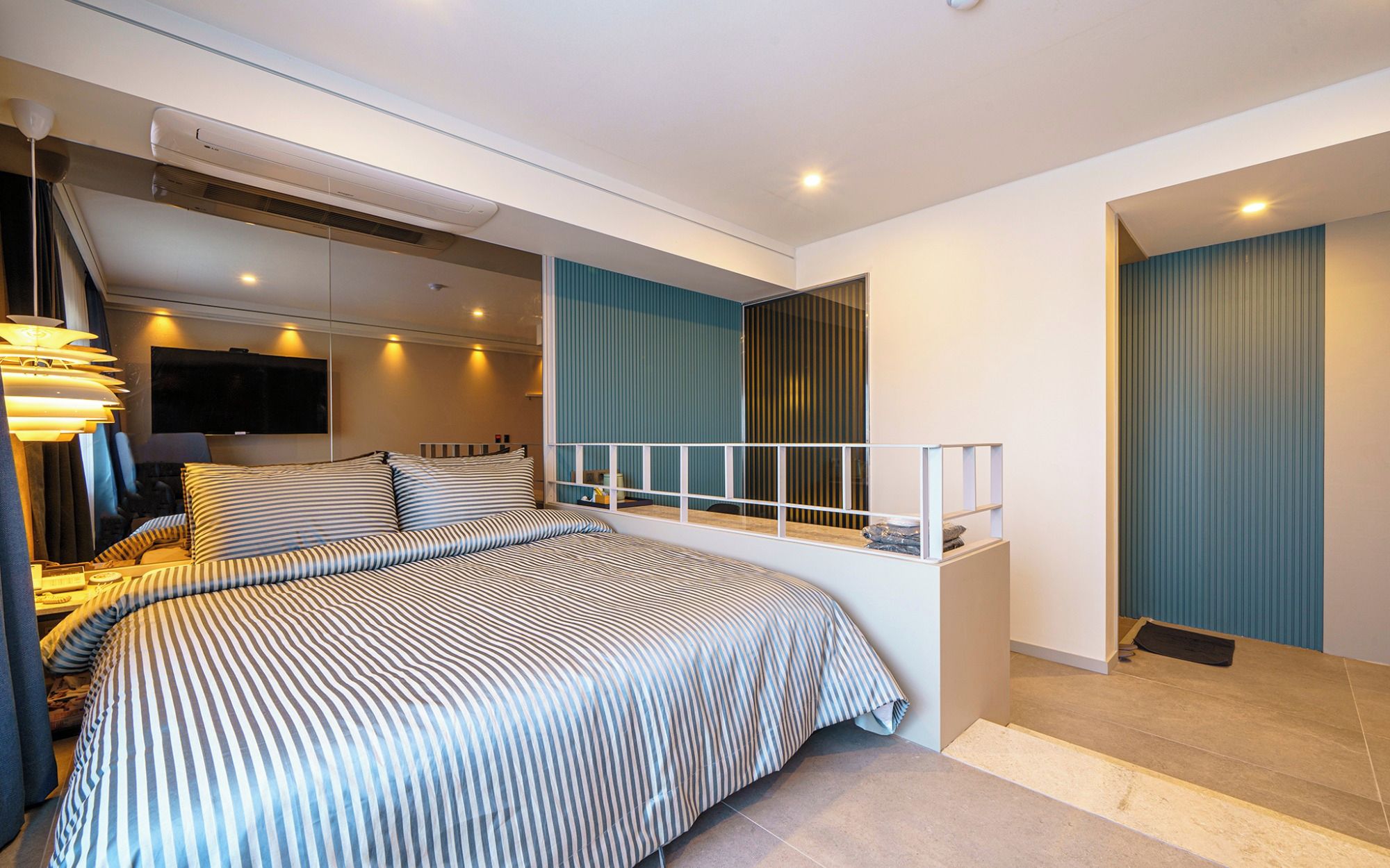 Quarto moderno com uma cama grande, televisão e varanda com guarda-corrimão.
