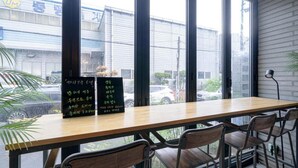 A restaurant with a wooden table and chairs, large windows, and a view of the street. - Busan Sasang Mr. Brick Hotel (Busan)