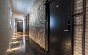 Ein Korridor mit einem Metallaufzug, einer Tür mit der Beschriftung '403' und einer Wand mit Ziegelmuster.